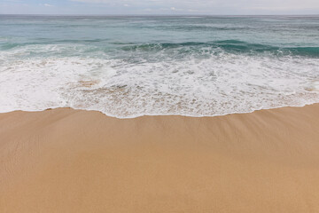 Wall Mural - Seascape background. Sandy beach, milky foam waves, blue ocean. Scenic waterscape. Horizon line. Nature and environment concept. Daylight. Copy space. Dreamland beach, Bali