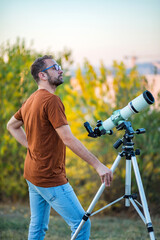 Wall Mural - amateur astronomer looking at the sky with a telescope.