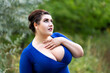 Sexy plus size model in blue dress with a deep neckline outdoors, beautiful fat woman with big breasts in nature