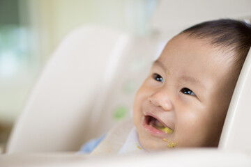 Wall Mural - 6 months old Asian baby eating food