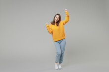 Full Length Of Young Smiling Positive Caucasian Happy Satisfied Woman 20s In Knitted Yellow Casual Sweater Do Winner Gesture Clench Fist Looking Camera Isolated On Grey Background Studio Portrait