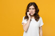 Young pensive thoughtful overthink mistaken troubled eueropean caucasian student woman 20s in white basic casual t-shirt look aside biting nails fingers isolated on yellow background studio portrait.