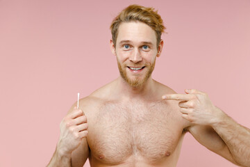 Wall Mural - Funny bearded naked young man 20s perfect skin point index finger on cotton swab stick for ear cleaning isolated on pink background studio portrait. Skin care healthcare cosmetic procedures concept.