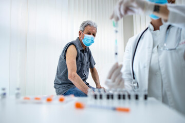 Senior man about to get vaccine shot in the clinic during corona virus pandemic to stay healthy. Immunization of older population.