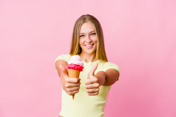 Wall Mural - Young russian woman eating an ice cream isolated with thumbs ups, cheers about something, support and respect concept.