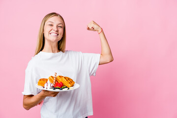 Wall Mural - Young russian woman eating a waffle isolated raising fist after a victory, winner concept.