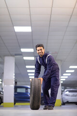 Wall Mural - Full-length Mechanic carrying a tire at motor garage	