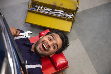 Wall Mural - Top angle view of a mechanic working under a vehicle	