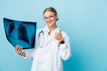 Wall Mural - Young russian doctor woman holding a bone scan on blue smiling and raising thumb up