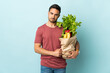 © luismolinero - Young caucasian man buying some vegetables isolated on blue background pleading