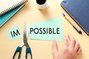 Poster - man hand holding card with the text impossible, cutting the word im so it written possible. success and challenge concept.