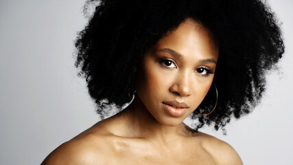 Wall Mural - Healthy, Clean, perfect facial skin. Beauty Portrait of a young female model of Afro-appearance posing. Working in a photo studio on a white background. Black healthy curly hair