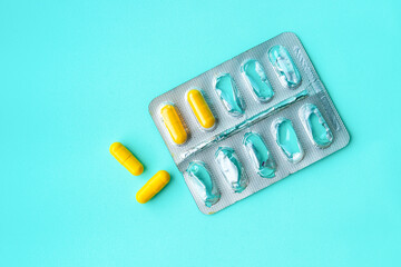 Half empty blister pack with yellow pills on light blue background