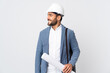 © luismolinero - Young architect man with helmet and holding blueprints isolated on white background looking side