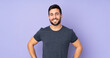 © luismolinero - Caucasian handsome man posing with arms at hip and smiling over isolated purple background