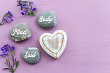 Zen Stones With The Words Mind Body Soul. Purple Wooden Background