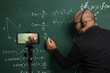 © Chanakon - Indian young teacher man wearing headset teaching online video conference live stream by smartphone. Asian teacher teaching mathematics class webinar online for students learning.