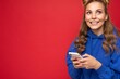 © Ivan Traimak - Photo shot of attractive positive good looking young woman wearing casual stylish outfit poising isolated on background with empty space holding in hand and using mobile phone messaging sms looking up
