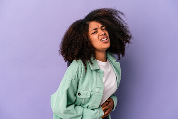 Wall Mural - Young african american curly woman isolated on purple background having a liver pain, stomach ache.