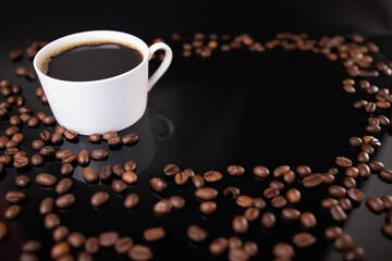 Poster - Cup of espresso and roasted beans on a black background with space for text