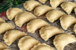 Dumplings before being boiled. Traditional Polish hand-made food. Polish pierogi arranged in rows close up