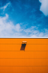 orange wall with lamp against blue sky