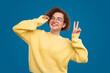 Cheerful woman in glasses showing v sign