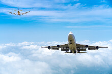 Two Commercial Passenger Aircraft Or Cargo Transportation Airplane Flying In Opposite Direction Over White Fluffy Cloud With Blue Sky