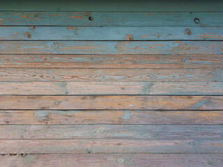 Texture of old wooden planks arranged horizontally with faded blue paint. Without people. Old village house made of wooden planks, with peeling paint. As a background or desktop wallpaper. 