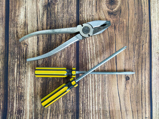 Steel pliers and screwdrivers on a wooden table