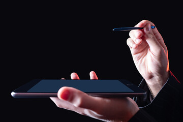 Poster - Close up of businessman hand using stylus pen for touching the digital tablet screen. Tablet and stylus close-up. Hands of a person with an electronic tablet on a dark background.