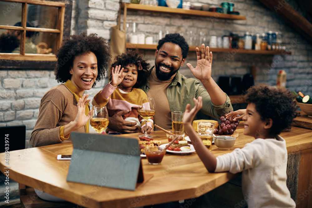 Happy black family waving during video call over touchpad at home ...