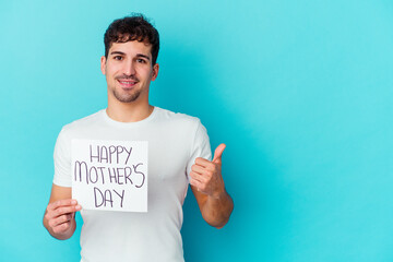 Wall Mural - Young caucasian man holding a happy mothers day placard isolated smiling and raising thumb up