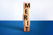 Merit symbol. Wooden cubes with the word 'merit'. Beautiful white and blue background, copy space. Business and merit concept.