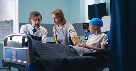 Wall Mural - Middle aged oncologist explaining treatment prospects to woman and boy