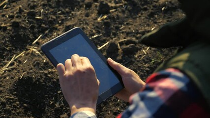 Wall Mural - man farmer red neck with a digital lifestyle tablet walking on land for sewing on soil a black field. eco agriculture farming concept. male worker studies winter dirt soil wheat crops works in field