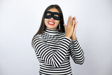 Fototapeta  - Young beautiful brunette burglar woman wearing mask clapping and applauding happy and joyful, smiling proud hands together