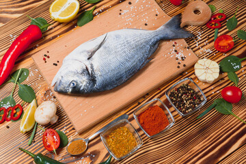 Wall Mural - Raw dorado fish with spices cooking on cutting board. Fresh fish dorado