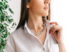 Silver bijouterie chain on woman neck. White background with green plant.