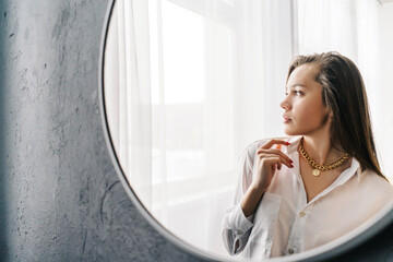 Wall Mural - Silver bijouterie chain with pendant on woman neck. Reflection woman in the mirror, window background.