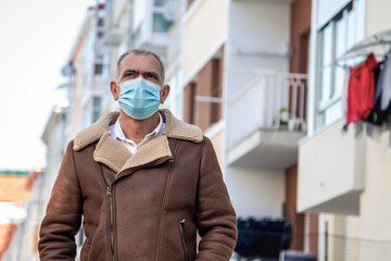 Wall Mural - attractive mature man with medical mask walking down the street