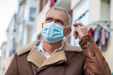 Wall Mural - attractive mature man putting medical mask on his face