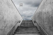 © Travelling Jack - Perspective of the exit staircase of a Milan underground station. Dramatic clouded sky on the background. Monochromatic.