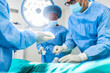 © Graphicroyalty - Surgeon and his assistant performing cosmetic surgery in hospital operating room. Surgeon in mask during medical procadure. Breast augmentation, enlargement, enhancement