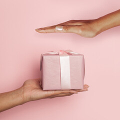 Wall Mural - Hand with gift on pink card background