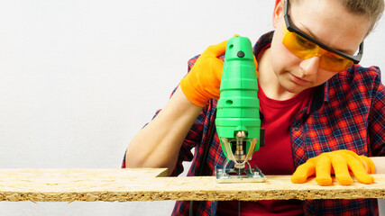 Close-up of cutting board with jigsaw, woman carpenter working on wood,