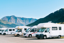 Summer Tourism With Rv In The Mountain. Campers Parked In A Row In A Caravan Parking Area. Best Option For Travel Feeling Free. Motorhomes And Campingcar.