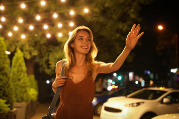 Wall Mural - Young woman catching taxi on city street at night