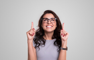 Excited woman in glasses pointing up