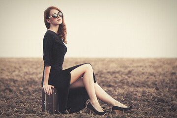 Wall Mural - Fashion redhead women with suitcase at autumn field